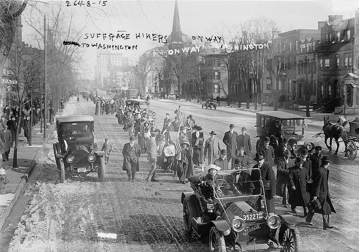 Broad Street
Photo shows the hike lead by "General" Rosalie Jones from New York to Washington, D.C. for the March 3, 1913 National American Woman Suffrage Association parade. Photo taken in Newark, New Jersey on Broad Street, just north of West Kinney Street, on February 12, 1913. Rosalie Jones is walking behind the first car. The church before City Hall is Grace Episcopal Church.

Photo from LOC
